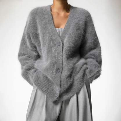 Grauer, flauschiger Strick-Cardigan mit V-Ausschnitt und Knöpfen, getragen über einem grauen Outfit. Modetrend, Damenbekleidung, Herbstmode.