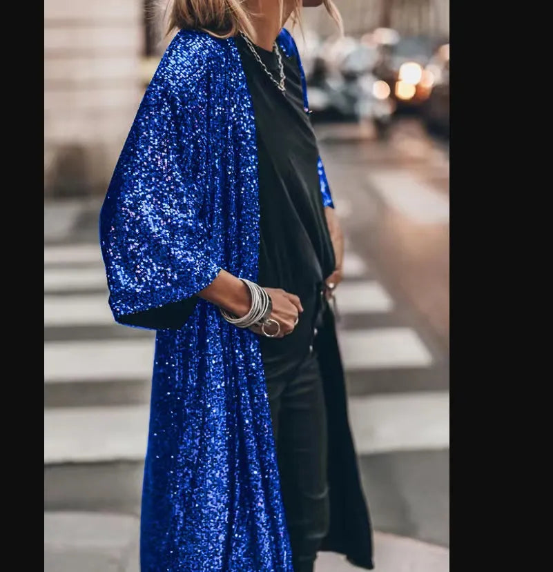Frau in blauem Paillettenmantel und schwarzem Outfit auf Straße. Modetrend, glamouröser Look, urbaner Stil, Abendmode.