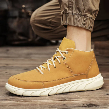 Beige Herren-Sneaker aus Leder mit weißer Sohle, getragen auf Holzboden. Modische, bequeme Schuhe für Freizeit und Outdoor-Aktivitäten.