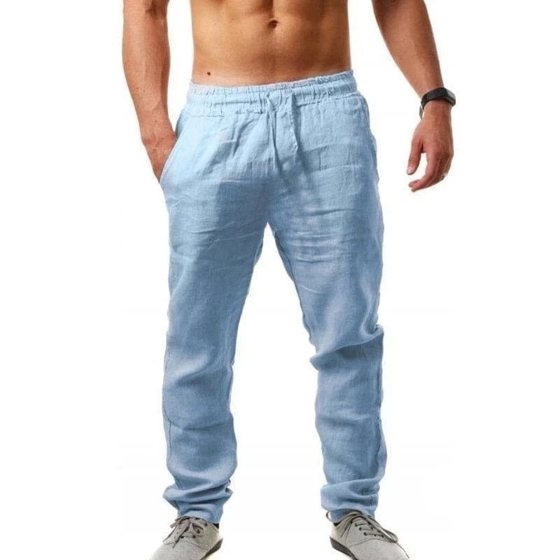 Mann in hellblauer Leinenhose, freier Oberkörper, trägt graue Sneaker. Bequeme Sommermode, lässiger Stil, ideal für Freizeit und Sport.