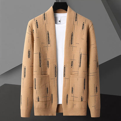 Beige Strickjacke mit schwarzem Blattmuster, hängend auf einem Kleiderbügel, vor grauem Hintergrund. Modische Herrenbekleidung, elegantes Design.