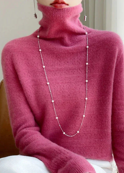 Frau in rosa Rollkragenpullover mit langer Perlenkette, elegantes Outfit, modischer Look, stilvolle Damenbekleidung, Herbstmode.