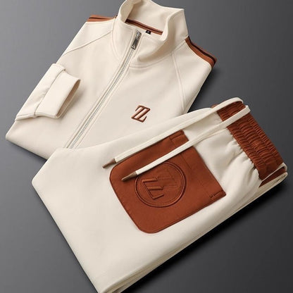 Beige-weißer Trainingsanzug mit braunen Akzenten, Reißverschlussjacke und elastischer Hose, stilvolles Sportoutfit, moderne Freizeitmode.