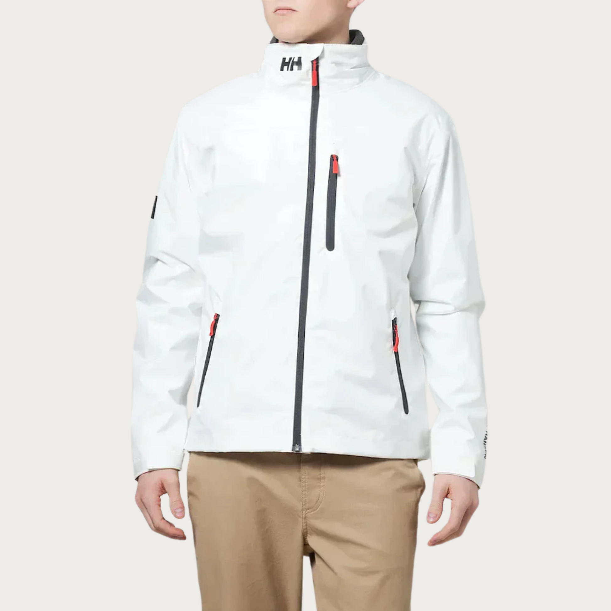 Weiße Helly Hansen Herrenjacke, wasserabweisend, mit Reißverschlusstaschen und Logo, getragen von einer Person in beigen Hosen.