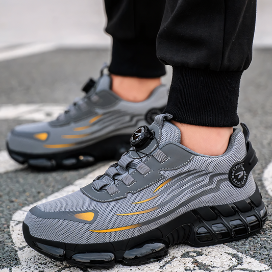 Graue Sportschuhe mit schwarzer Sohle und gelben Akzenten auf Asphalt. Moderne Turnschuhe, ideal für Laufen und Fitness. Bequeme, stilvolle Sneaker.