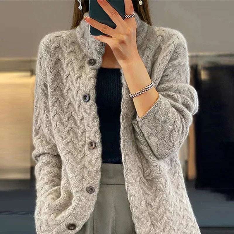 Frau in grauer Strickjacke mit Zopfmuster, schwarzem Top und grauer Hose. Modetrend, Herbstmode, Damenbekleidung, eleganter Look.