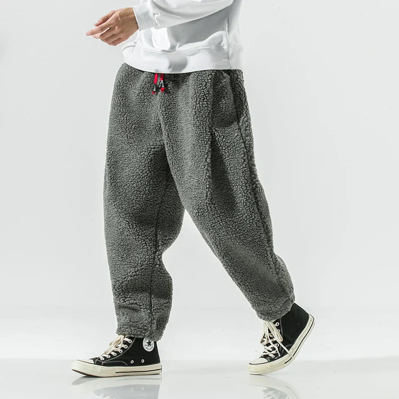 Graue Fleece-Jogginghose für Herren, bequem und warm, ideal für Freizeit und Sport. Kombiniert mit schwarzen High-Top-Sneakern.