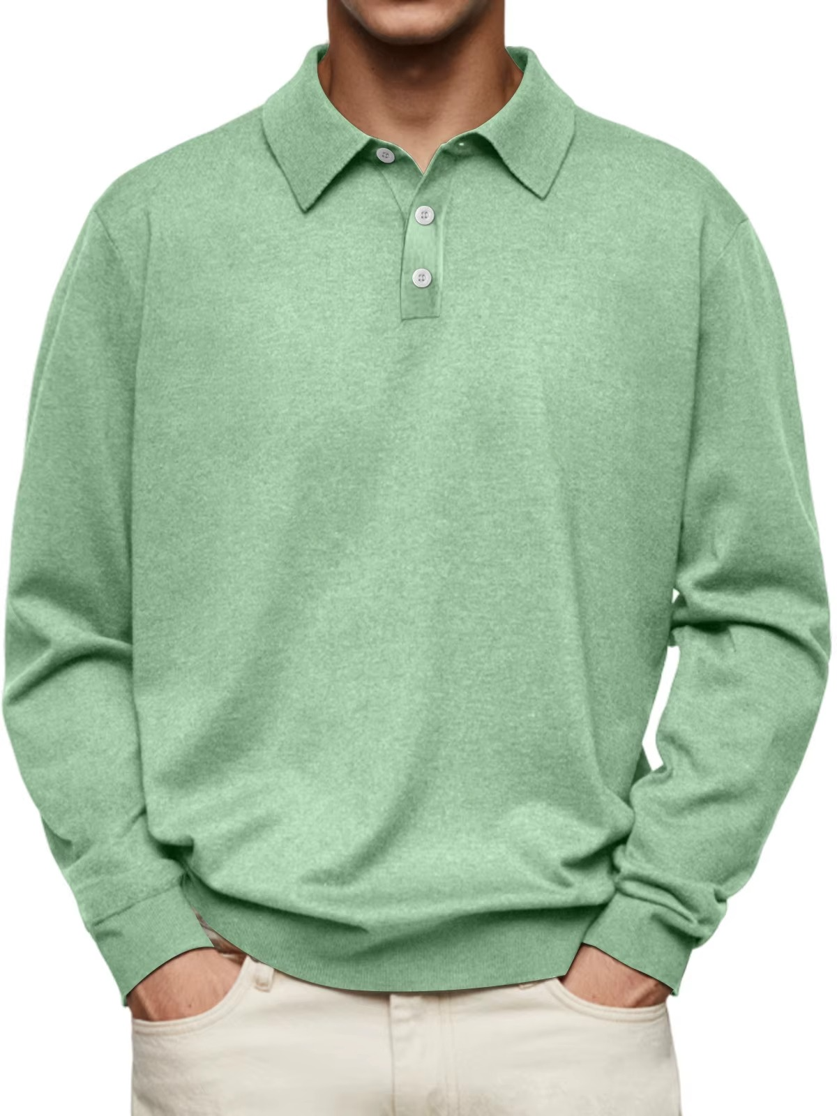 Mann trägt grünes Poloshirt aus Baumwolle, langärmlig, mit Knopfleiste, kombiniert mit beigen Hosen. Elegante Freizeitmode für Herren.