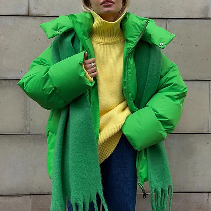 Frau in grüner Daunenjacke und gelbem Rollkragenpullover vor Betonwand. Wintermode, warme Kleidung, modischer Streetstyle.