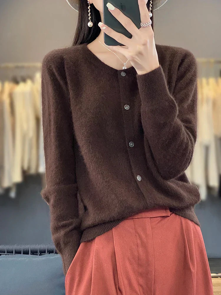 Frau in braunem Strickpullover und roter Hose, hält Smartphone. Modetrend, Herbstmode, elegante Damenbekleidung, stilvoller Look.