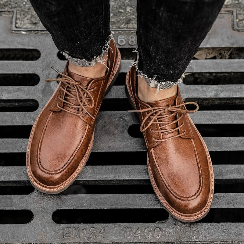 Braune Lederschuhe für Herren auf Gitterrost, getragen mit schwarzen Jeans. Elegante Schnürschuhe, ideal für stilvolle Freizeit- und Business-Outfits.