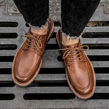 Braune Lederschuhe für Herren auf Gitterrost, getragen mit schwarzen Jeans. Elegante Schnürschuhe, ideal für stilvolle Freizeit- und Business-Outfits.
