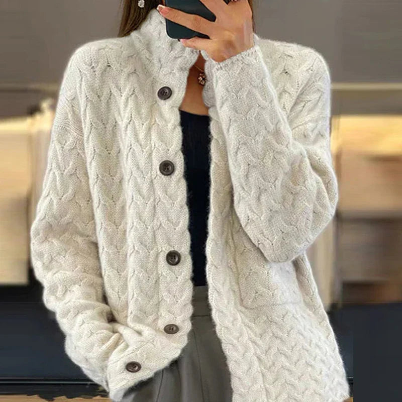 Frau trägt cremefarbene Strickjacke mit Zopfmuster und Knöpfen, modisch und warm, ideal für Herbst und Winter. Elegante Damenmode.