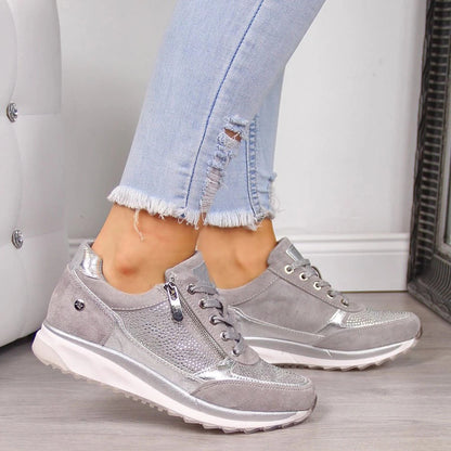 Graue Damen-Sneaker mit silbernen Details, kombiniert mit hellblauen, zerrissenen Jeans. Modische Freizeitschuhe für Damen, ideal für den Alltag.