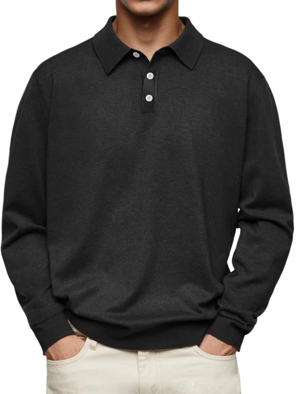 Mann trägt schwarzen Langarm-Poloshirt mit Knopfleiste, kombiniert mit hellen Hosen. Elegante Freizeitmode für Herren, ideal für Herbst und Winter.
