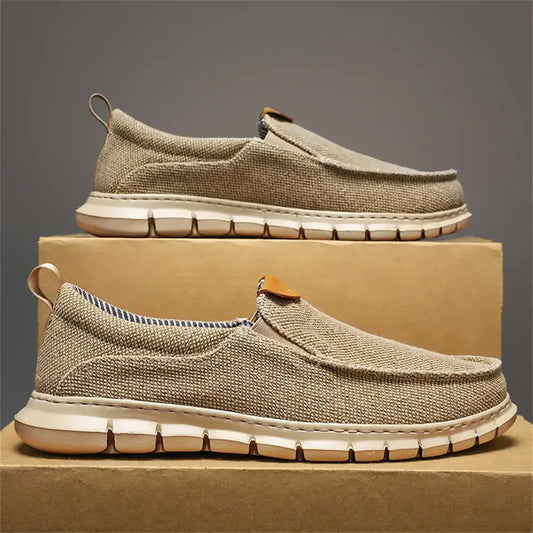 Beige Herren-Sneaker aus Leinen auf Karton, seitliche Ansicht. Bequeme, atmungsaktive Freizeitschuhe mit flexibler Sohle. Ideal für Alltag und Reisen.