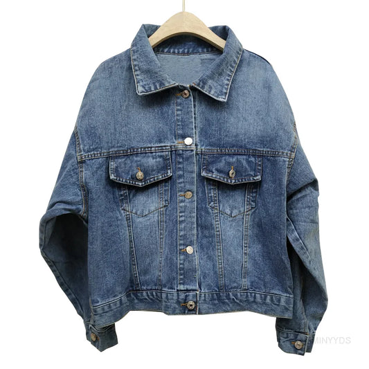 Blaue Jeansjacke auf Holzkleiderbügel, klassisches Design mit Knopfleiste und Brusttaschen, lässige Damenmode, zeitloser Denim-Look.