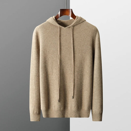 Beiger Kapuzenpullover aus Kaschmir, hängend auf Holzkleiderbügel vor zweifarbigem Hintergrund. Elegante Herrenmode, weicher Stoff, stilvoller Look.