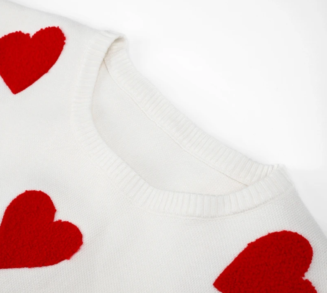 Weißer Pullover mit roten Herzmotiven, weicher Strickstoff, modisches Design, ideal für romantische Anlässe und Valentinstag.