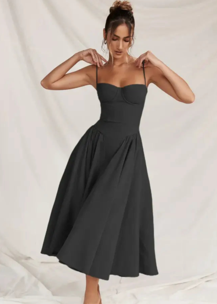 Frau in elegantem, schwarzem Abendkleid mit Spaghettiträgern, posiert vor weißem Hintergrund. Mode, Damenbekleidung, Abendmode.