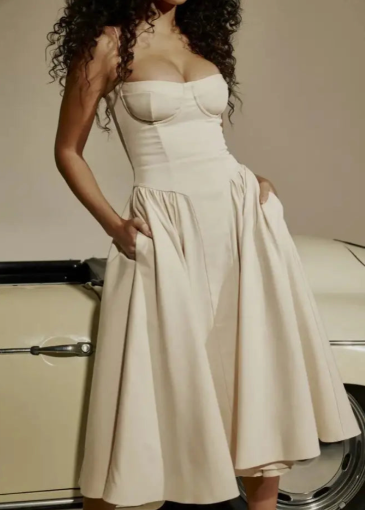 Frau in elegantem, cremefarbenem Korsettkleid vor klassischem Auto. Mode, Abendkleid, Vintage-Stil, Luxus, zeitlose Eleganz.