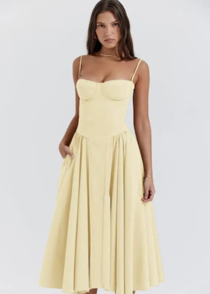 Frau in elegantem, gelbem Sommerkleid mit Spaghettiträgern und ausgestelltem Rock. Mode, Damenbekleidung, stilvolles Design, Sommeroutfit.