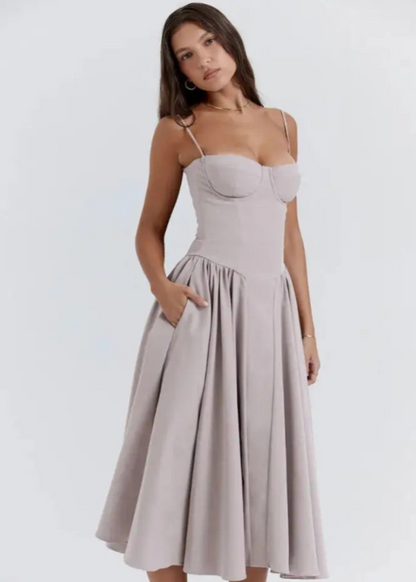 Frau in elegantem, grauem Kleid mit Spaghettiträgern und ausgestelltem Rock. Mode, Damenbekleidung, stilvolles Abendkleid, zeitloses Design.