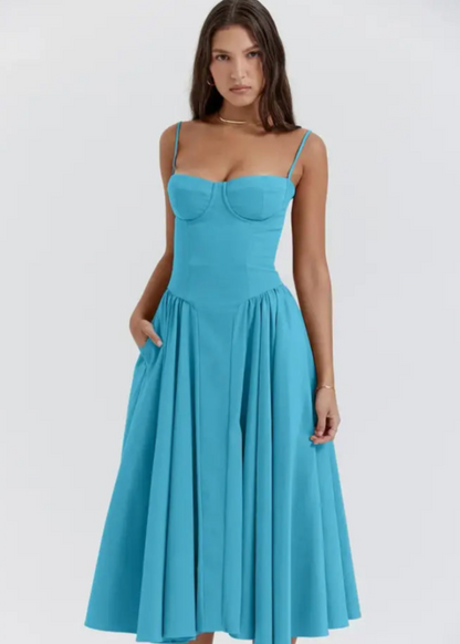 Frau in elegantem, blauem Sommerkleid mit Spaghettiträgern und ausgestelltem Rock, ideal für festliche Anlässe und modische Sommeroutfits.