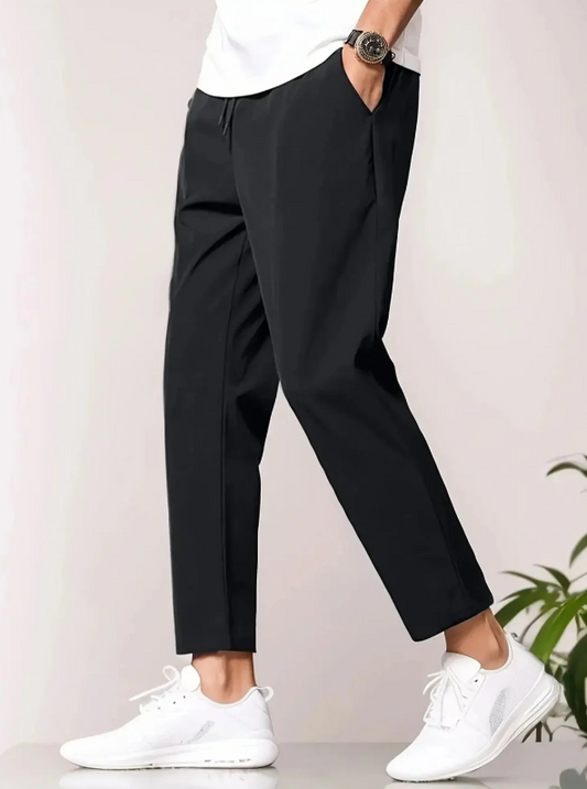 Mann trägt schwarze Chino-Hose und weiße Sneaker, seitliche Ansicht. Moderne Herrenmode, lässiger Stil, ideal für Freizeit und Alltag.