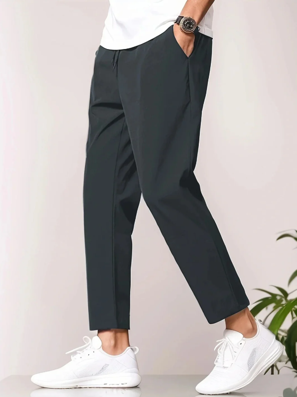 Herrenmode: Schwarze Chinohose, kombiniert mit weißen Sneakers und weißem T-Shirt. Stilvolle Freizeitkleidung für Männer.