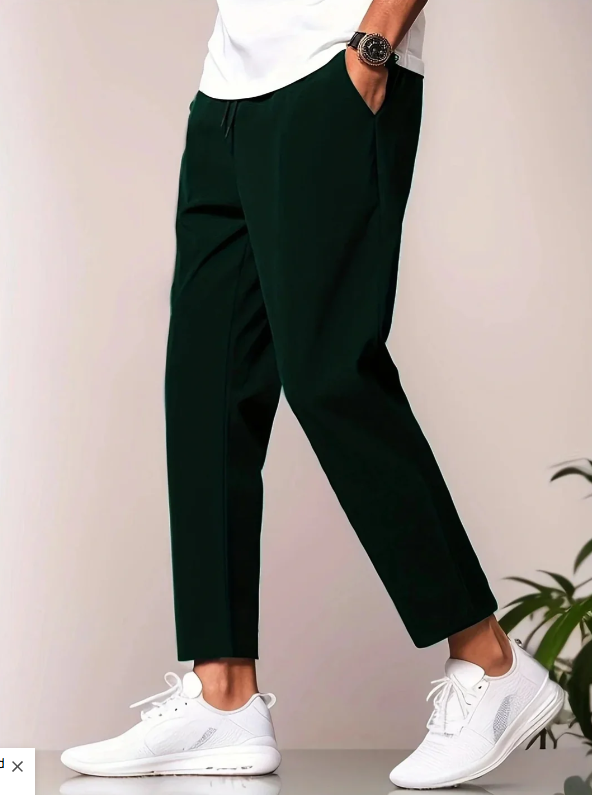 Mann trägt dunkelgrüne Chinohose und weiße Sneaker, seitliche Ansicht. Stilvolle Herrenmode, lässiger Look, moderne Freizeitkleidung.
