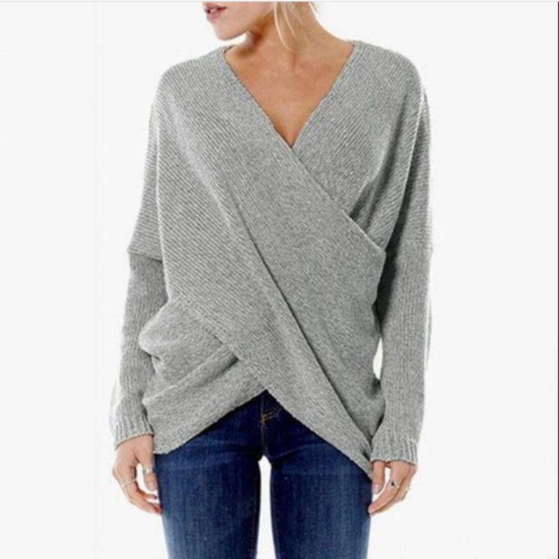 Grauer Damen-Wickelpullover aus Strick, kombiniert mit blauer Jeans. Modischer, bequemer Look für Herbst und Winter. Ideal für Freizeitkleidung.