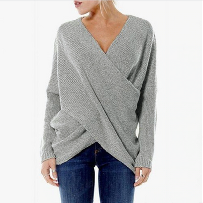 Grauer Damen-Wickelpullover aus Strick, kombiniert mit blauer Jeans. Modischer, bequemer Look für Herbst und Winter. Ideal für Freizeitkleidung.