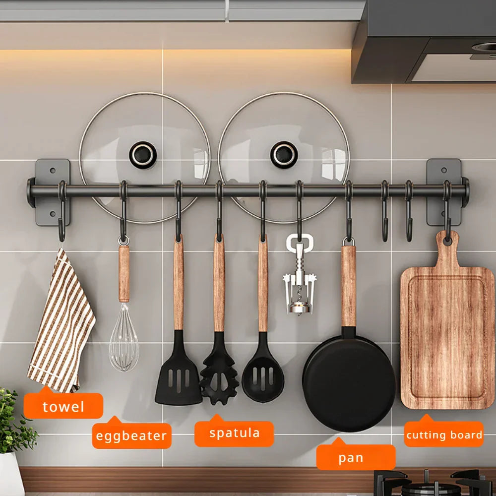 Küchenutensilien-Set an Wandhalterung: Pfanne, Schneebesen, Spatel, Schneidebrett, Topfdeckel. Praktische Küchenorganisation, modernes Design.