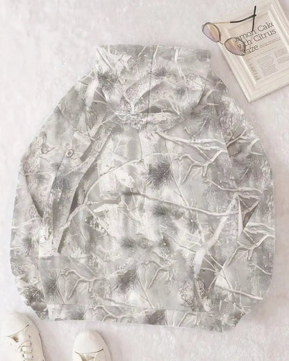 Grauer Camouflage-Hoodie mit Waldmuster auf weißem Hintergrund, daneben Sonnenbrille und Zeitschrift. Perfekt für Outdoor-Mode und Freizeitkleidung.