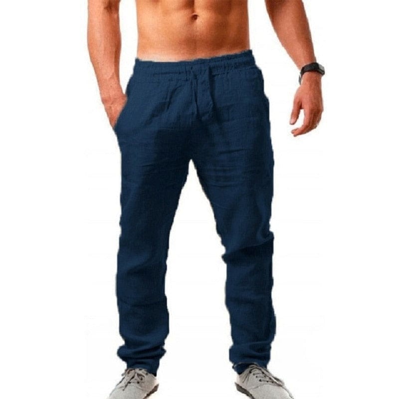 Mann in blauer Jogginghose, freier Oberkörper, trägt graue Sneaker. Sportliche Freizeitmode, bequem und modern.