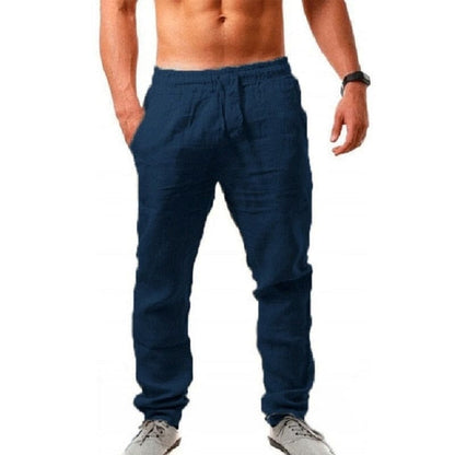 Mann in blauer Jogginghose, freier Oberkörper, trägt graue Sneaker. Sportliche Freizeitmode, bequem und modern.