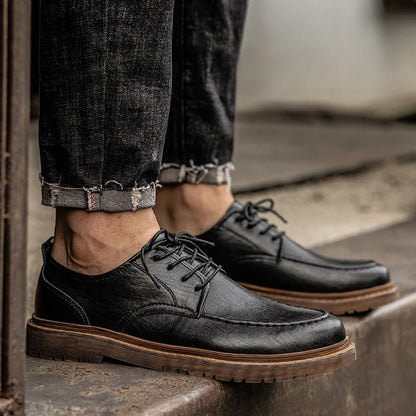 Schwarze Lederschuhe für Herren, kombiniert mit hochgekrempelten Jeans. Stilvolle, robuste Schnürschuhe, ideal für Freizeit und Business.