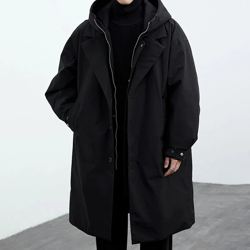Schwarzer Oversize-Mantel mit Kapuze, getragen von einer Person. Modischer Wintermantel, ideal für kaltes Wetter. Eleganter, minimalistischer Stil.