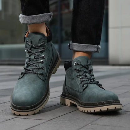 Graue Herren-Wanderschuhe aus Leder, robustes Design, geschnürt, auf grauem Pflaster getragen. Ideal für Outdoor-Aktivitäten und modische Herbst-Looks.