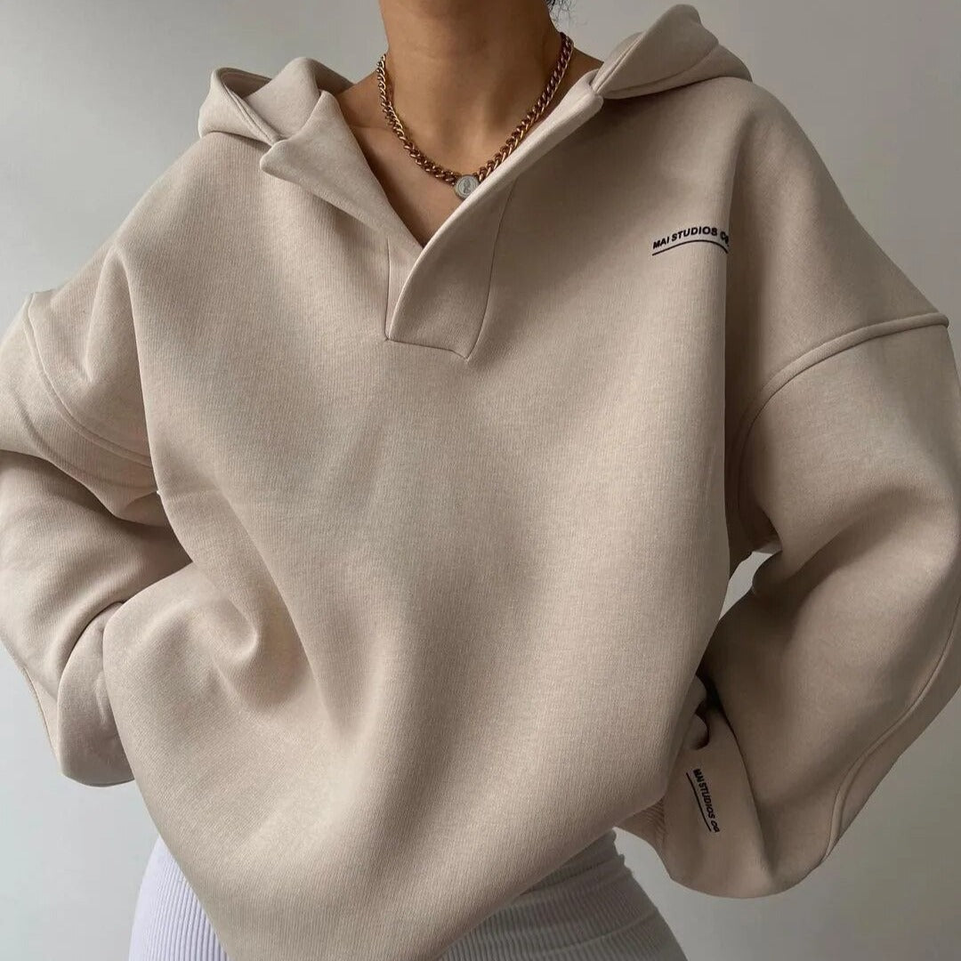 Frau trägt beigen Hoodie mit Kapuze und Kette, minimalistisch, modisch. Perfekt für lässigen Stil und Streetwear-Trends.