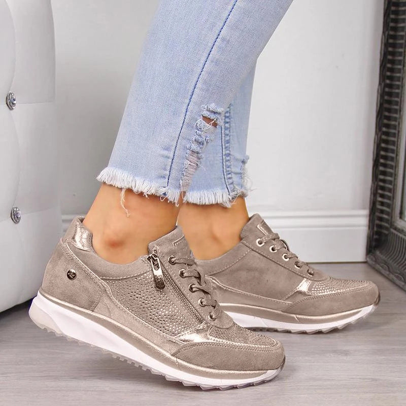 Damen Sneaker in Beige mit Metallic-Details, kombiniert mit hellblauen, zerrissenen Jeans. Modische Freizeitschuhe, ideal für den Alltag.