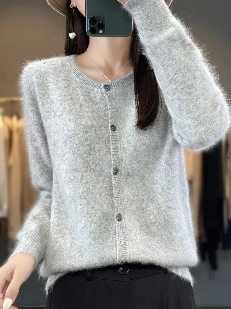Dame in grauem Strickcardigan mit Knöpfen, hält Smartphone. Modischer Herbst-Look, weicher Stoff, elegantes Design. Ideal für kühle Tage.