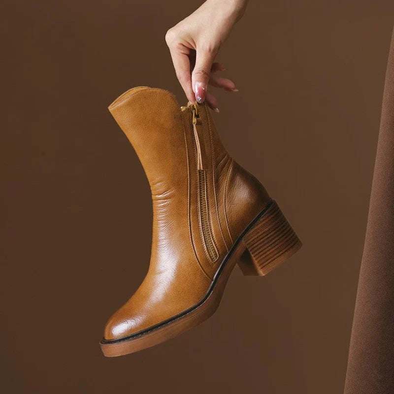 Brauner Damenstiefel mit Blockabsatz und Reißverschluss, in Hand gehalten. Modischer Lederstiefel, ideal für Herbst- und Winteroutfits.