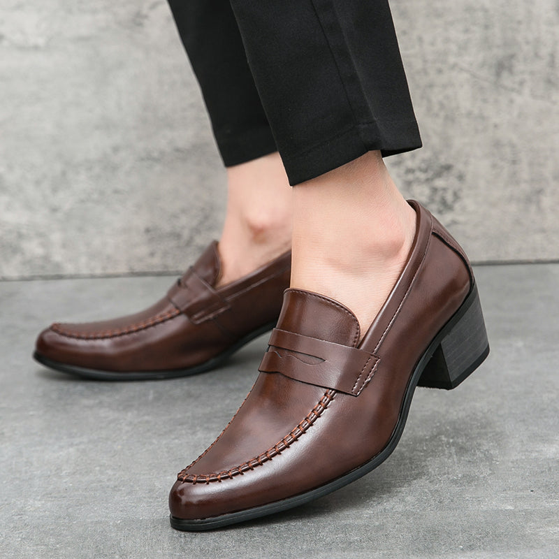 Braune Herren-Lederloafer mit Absatz, getragen zu schwarzer Hose. Elegante, klassische Schuhe für Business und Freizeit. Hochwertige Verarbeitung.