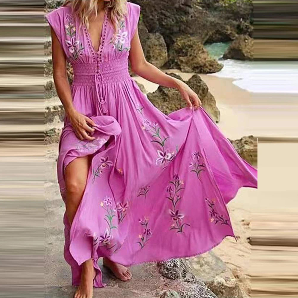 Frau in rosa Sommerkleid mit Blumenstickerei am Strand, hebt den Rocksaum an. Perfekt für Strandmode, Boho-Stil, Sommerkleider.