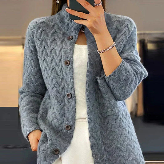 Frau trägt graue Strickjacke mit Zopfmuster und Knöpfen, kombiniert mit weißem Oberteil. Modetrend, Damenmode, Herbstbekleidung.