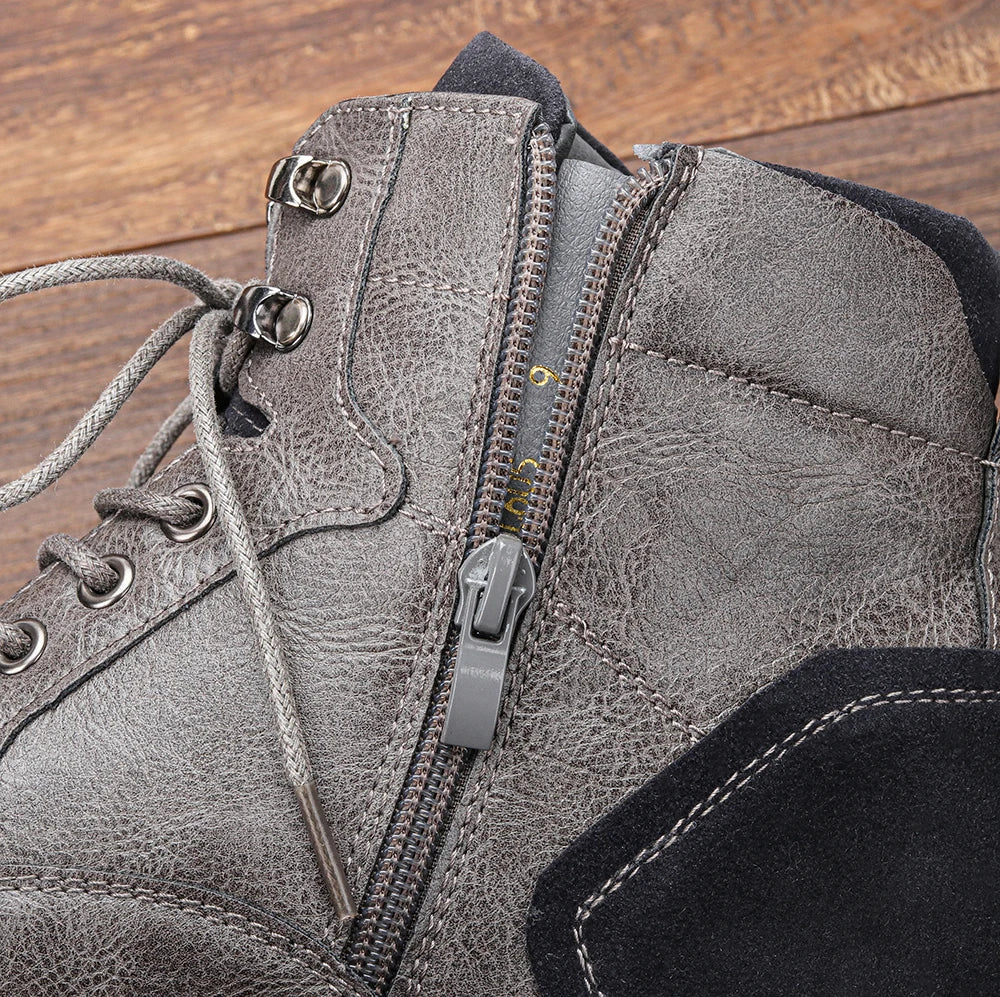 Grauer Lederstiefel mit Reißverschluss und Schnürsenkeln auf Holzboden. Robustes Design, ideal für Outdoor-Aktivitäten und modische Herbst-Looks.