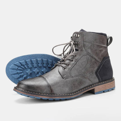 Graue Herrenstiefel aus Leder mit blauer Profilsohle, Schnürung und Holzabsatz. Modische, robuste Winterstiefel für Herren.