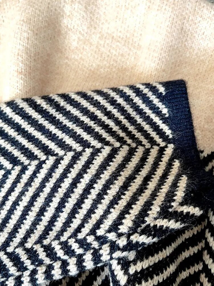 Schwarz-weiß gestreifter Strickpullover mit Zickzackmuster auf beigem Hintergrund. Modetrend, Strickmode, Winterkleidung, Textildesign.